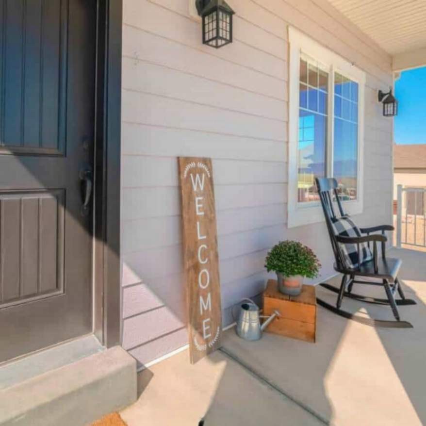 Farmhouse porch with a "Welcome" sign, rocking chair, and cozy decor accents.