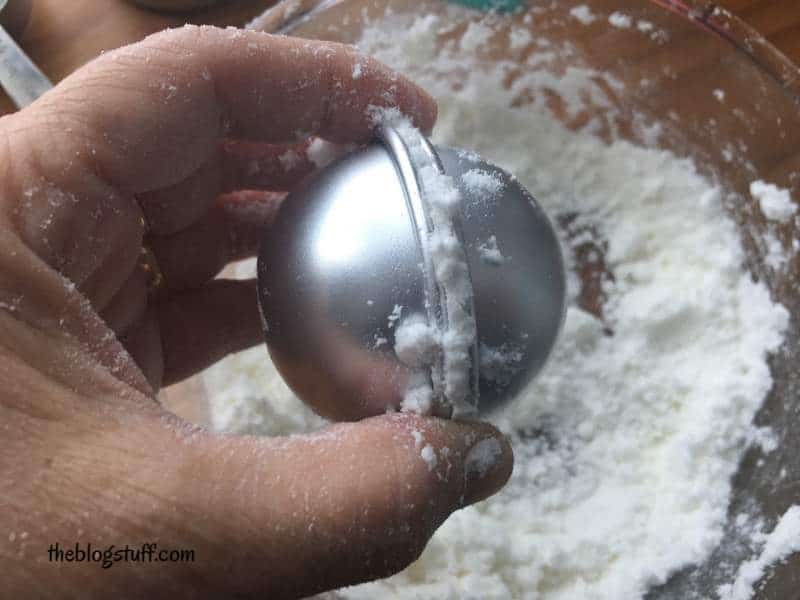 Pressing both halves of the mold together to make a bath bomb