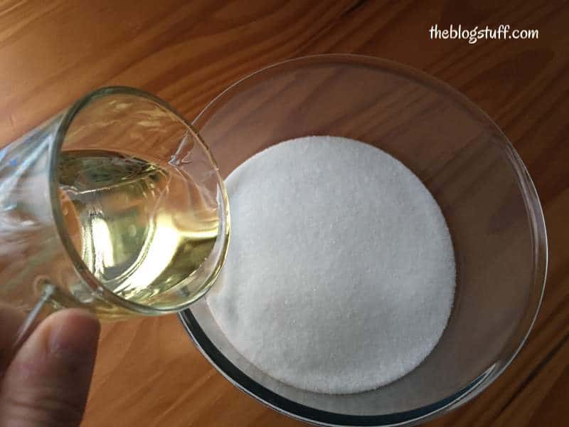 Pouring almond oil into sugar in a bowl