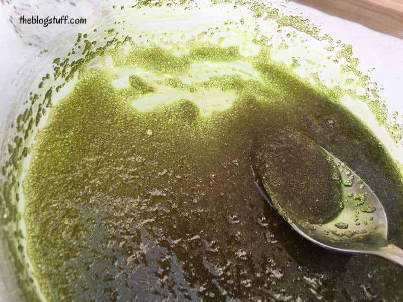 Sugar scrub with green colorant in a bowl and a spoon 