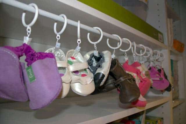 Baby shoes are organized on a rail in a closet