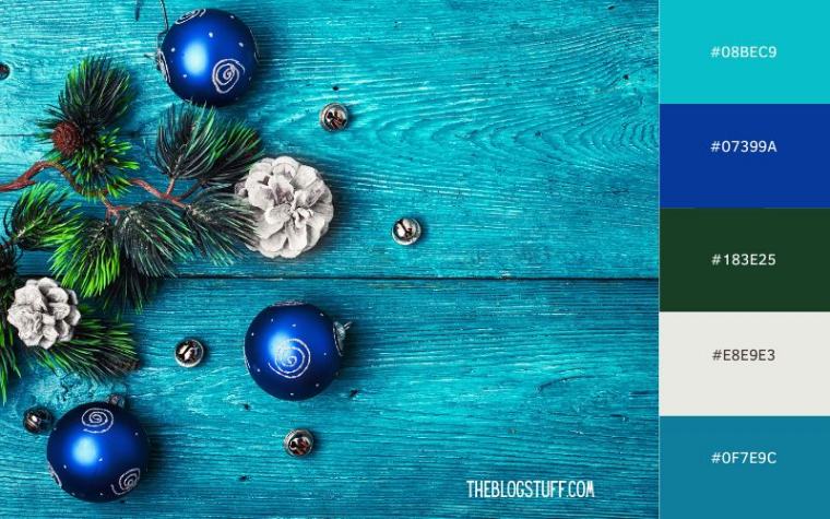 Icy blue Christmas baubles and evergreen sprigs on a rustic blue wooden background, creating a cool and modern holiday theme.