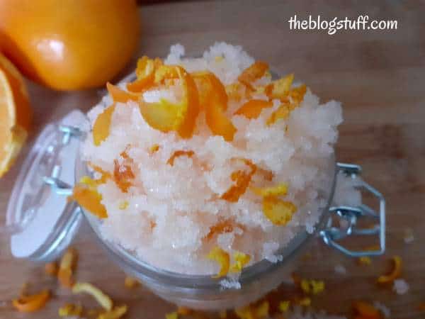 Homemade orange sugar scrub in an open glass jar