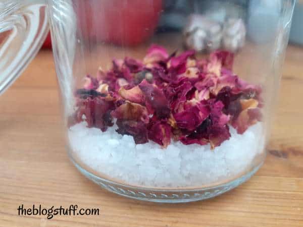 Dead sea salts and dried roses at the bottom of a container