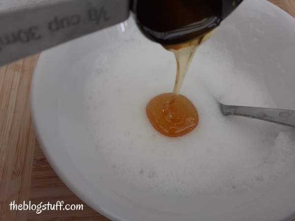 Pouring honey on whisked egg white to make a DIY face mask by The Blog Stuff