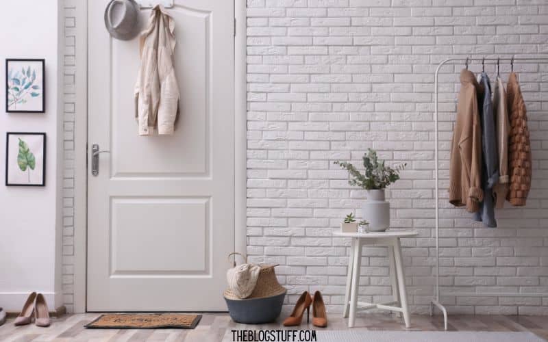 Entryway with white brick walls, a coat rack, and neatly arranged decor