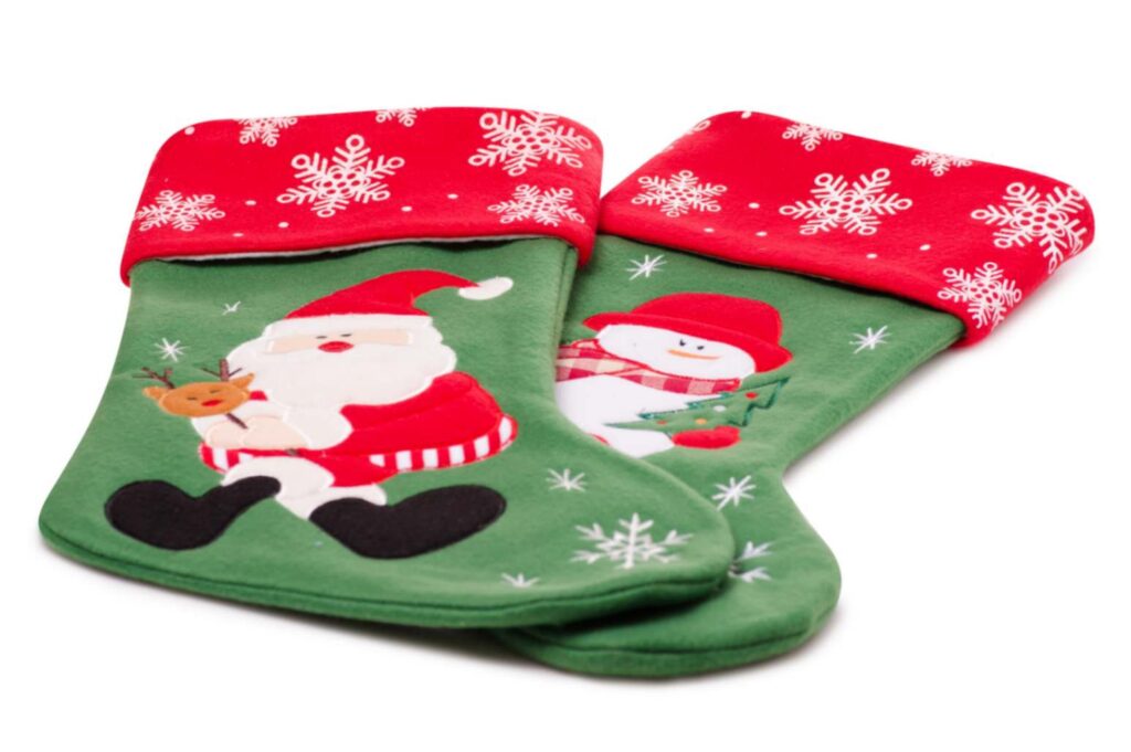 Two flat Christmas stockings, one with a Santa design and the other with a snowman, decorated with red cuffs featuring snowflake patterns ready for storage.