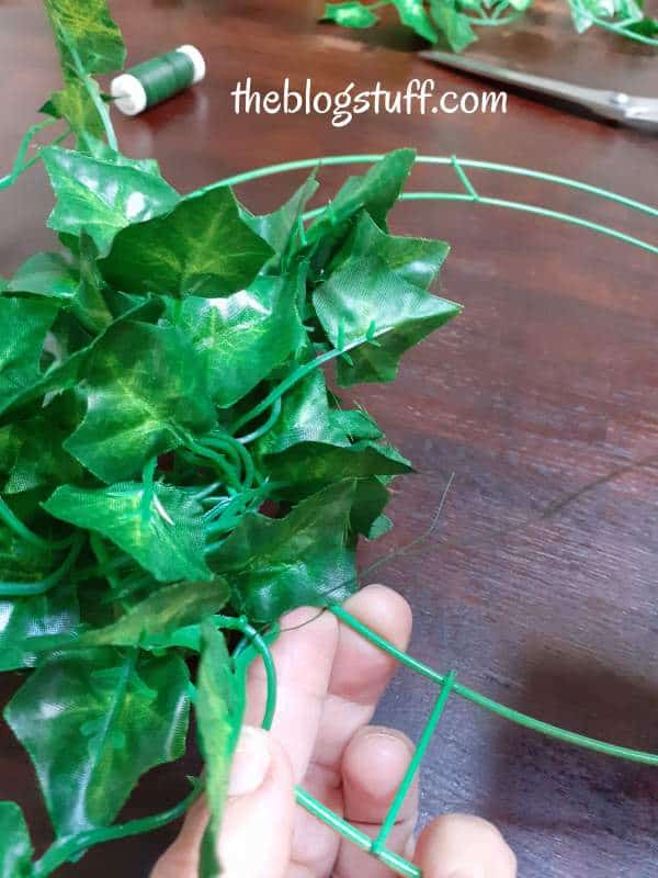 Attaching greenery around a metal hoop 