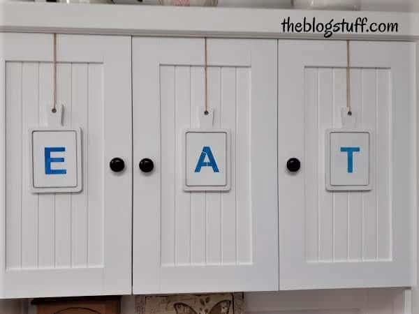 3 wooden cutting boards hanging from kitchen cabinets