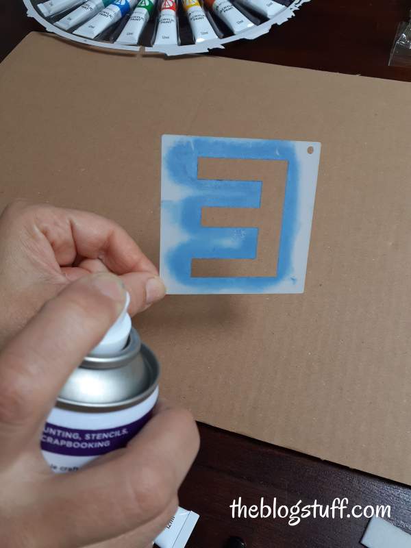 Spraying glue to the back of a stencil