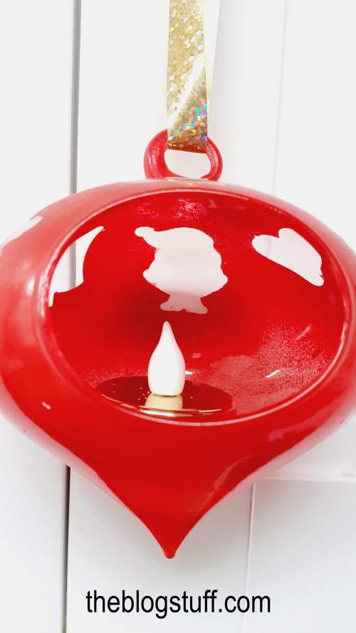 DIY Christmas bauble with faux candle hanging from a cabinet