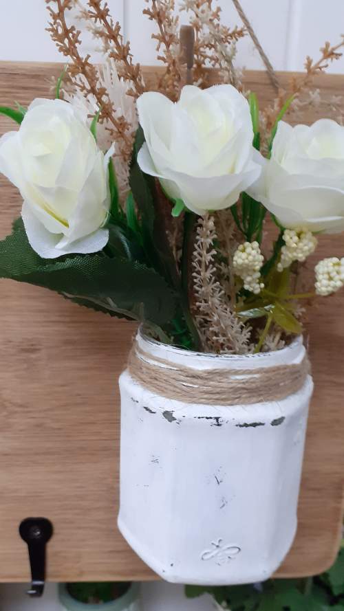 Flower on glass jar attached to wood board