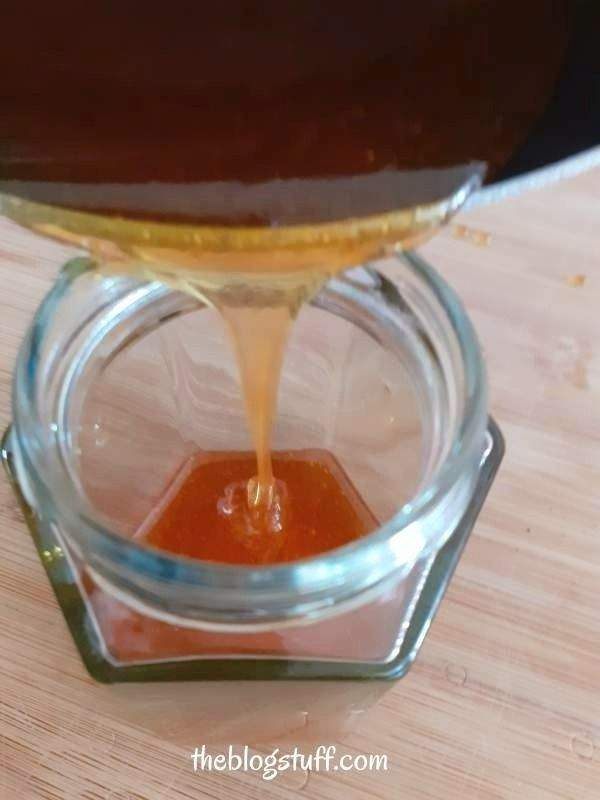 Pouring lemon sugar wax into a glass jar