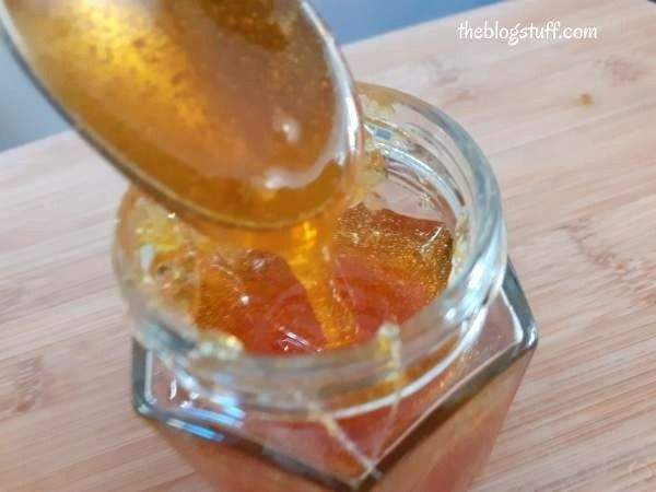 Taking DIY sugar wax with a spoon from a glass jar