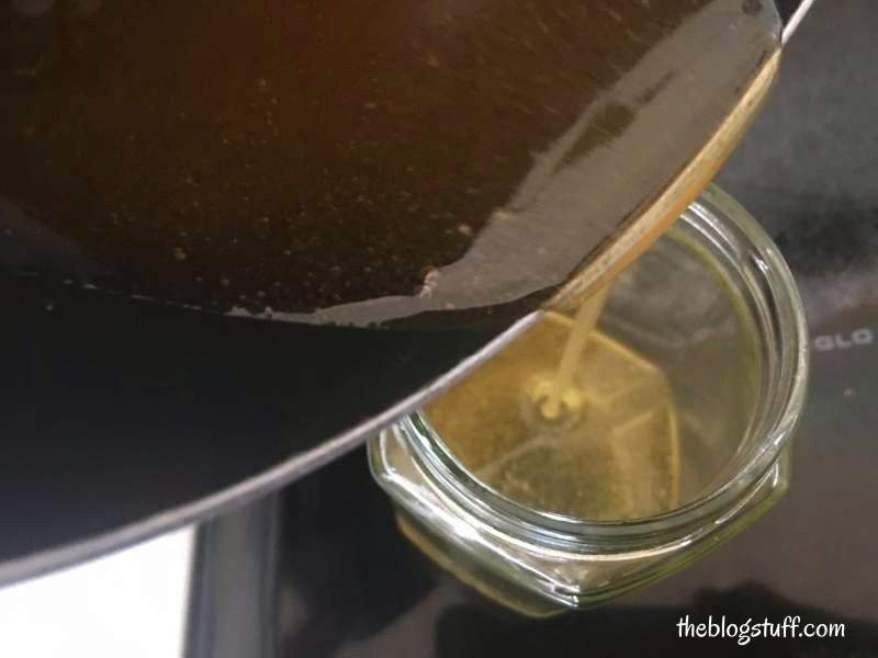 Pouring vinegar sugar wax into a glass jar