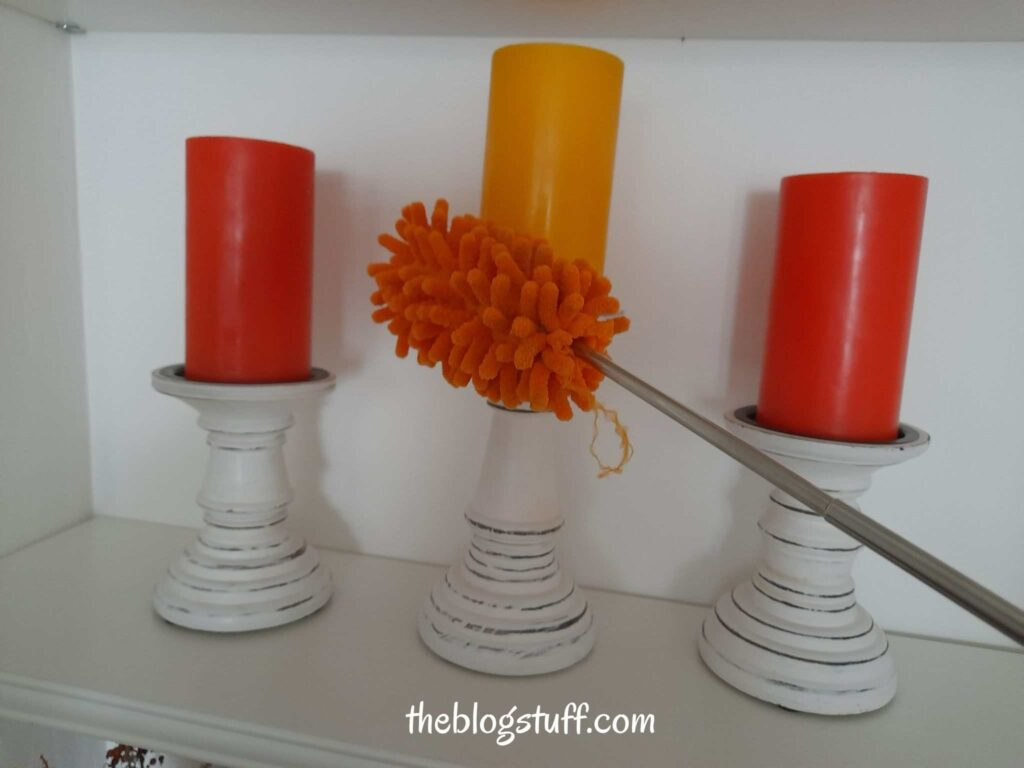 Dusting candle holders on shelves