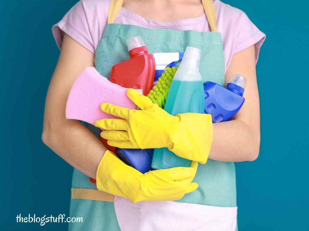 Woman with yellow gloves and cleaning supplies in her arms