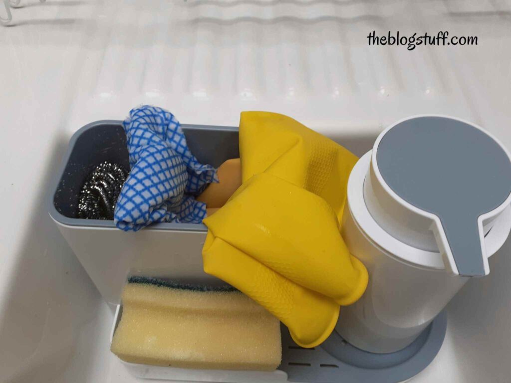 Over-the-sink organizer with sponges, cleaning cloth, and yellow gloves