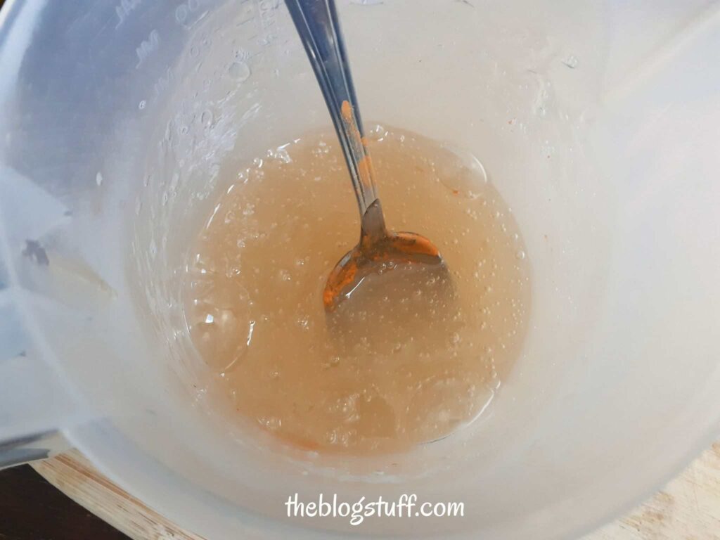 Stirring glycerin soap and orange mica powder with a spoon