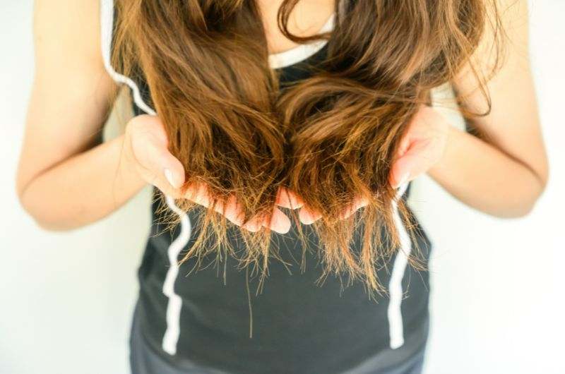 A woman with hair split ends in her hands