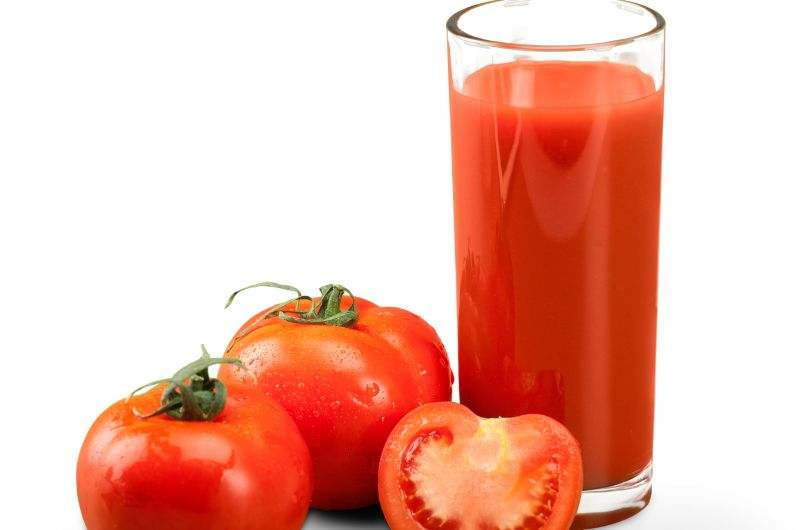 Tomato juice in a glass and 3 tomatoes