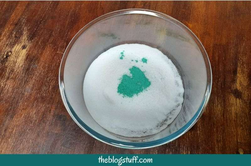 Baking soda, citric acid, colorant, and essential oils in a mixing bowl