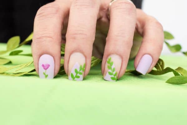 Square lavender and beige color nails with floral patterns in 3 of the nails