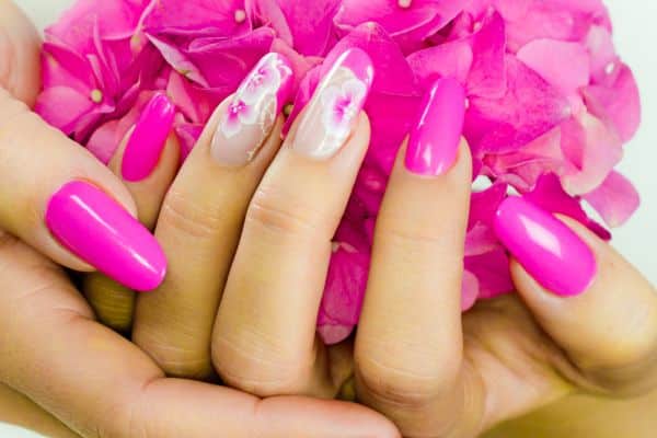 Hot pink nails with a spring white flower design in some of the nails