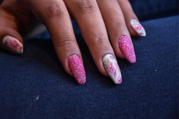 Almond shaped nails with pink glitter and a vintage floral desing in some nails