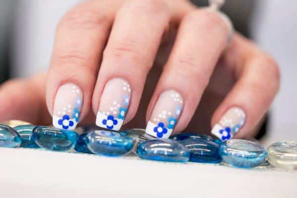 Nails with a milky white base and blue floral patterns