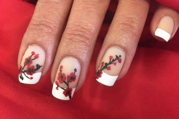 French manicure nails with a white tip and red and black floral pattern