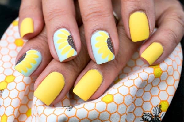 Yellow square nails with a sunflower design on some of the nails