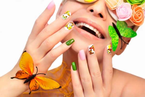 Green, pink and white nails with colorful butterflies in some of the nails