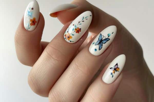 Almond shaped glossy white nails with floral and butterfly designs