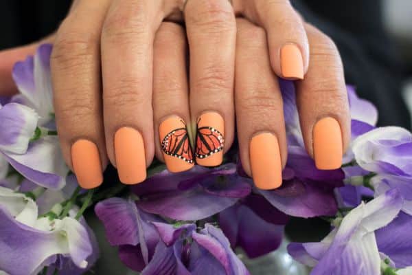 Orange nails with butterflies in two nails