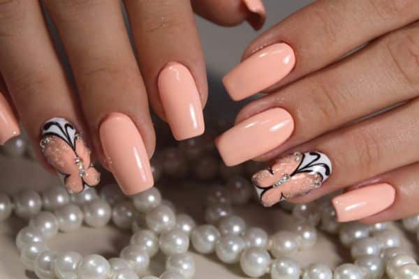 Long soft peach nails with a butterfly design in two of the nails