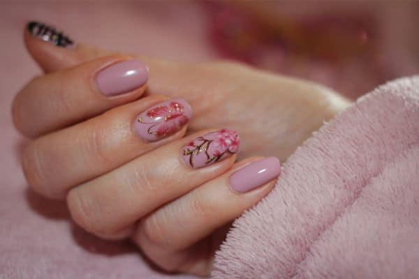 Soft pink nails with a butterfly design and a floral pattern in some nails