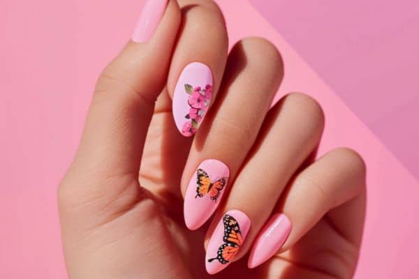 Almond nails in pink color with orange butterflies in two nails