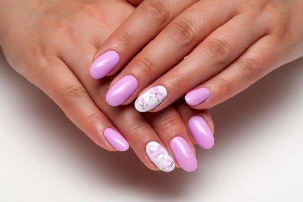 Pastel pink nails decorated with tiny butterflies and dots in two of the nails