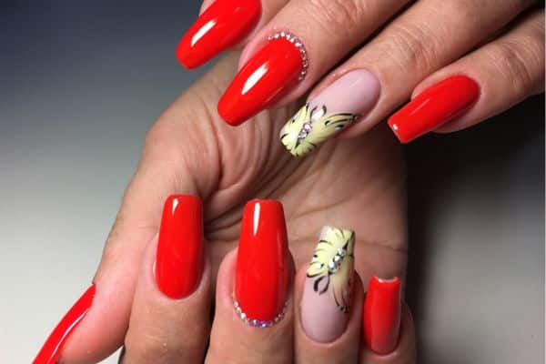 Long glossy red nails with a pink nail polisg and a butterfly design in two of the nails