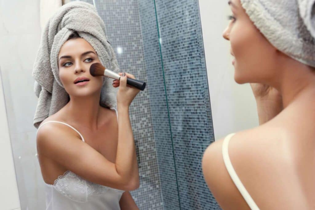 A woman applying blusher to her cheeks