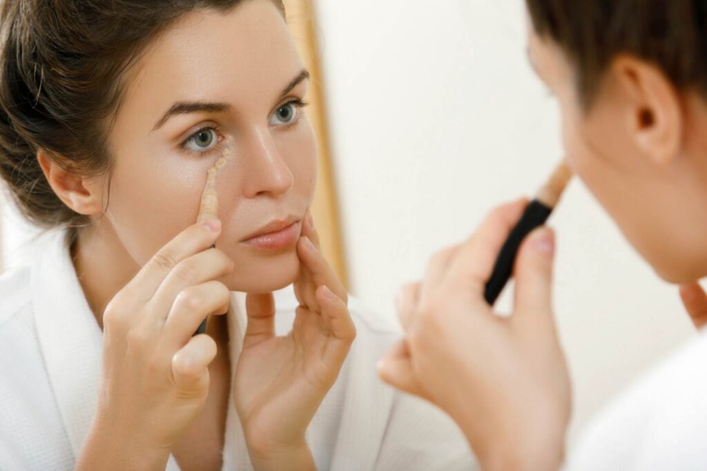 A woman applying concealer underneath the eyes