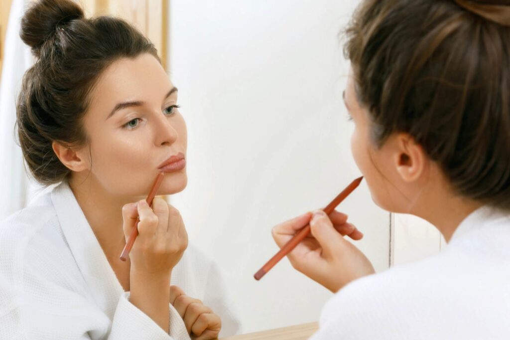 A woman applying lip liner on her lips