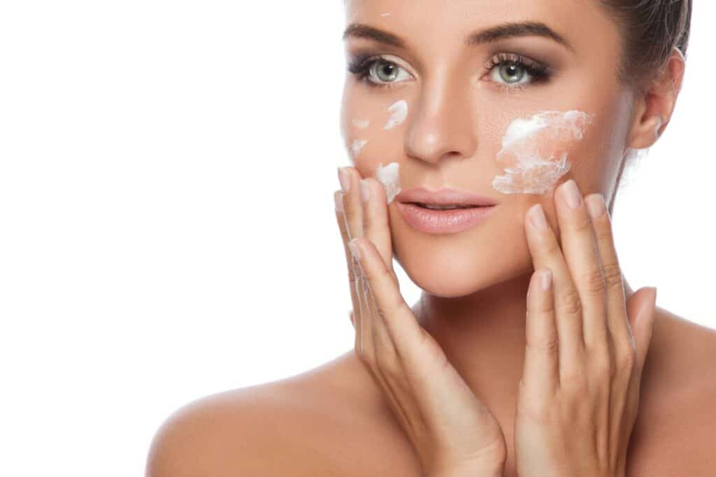 A woman applying moisturizer to her face