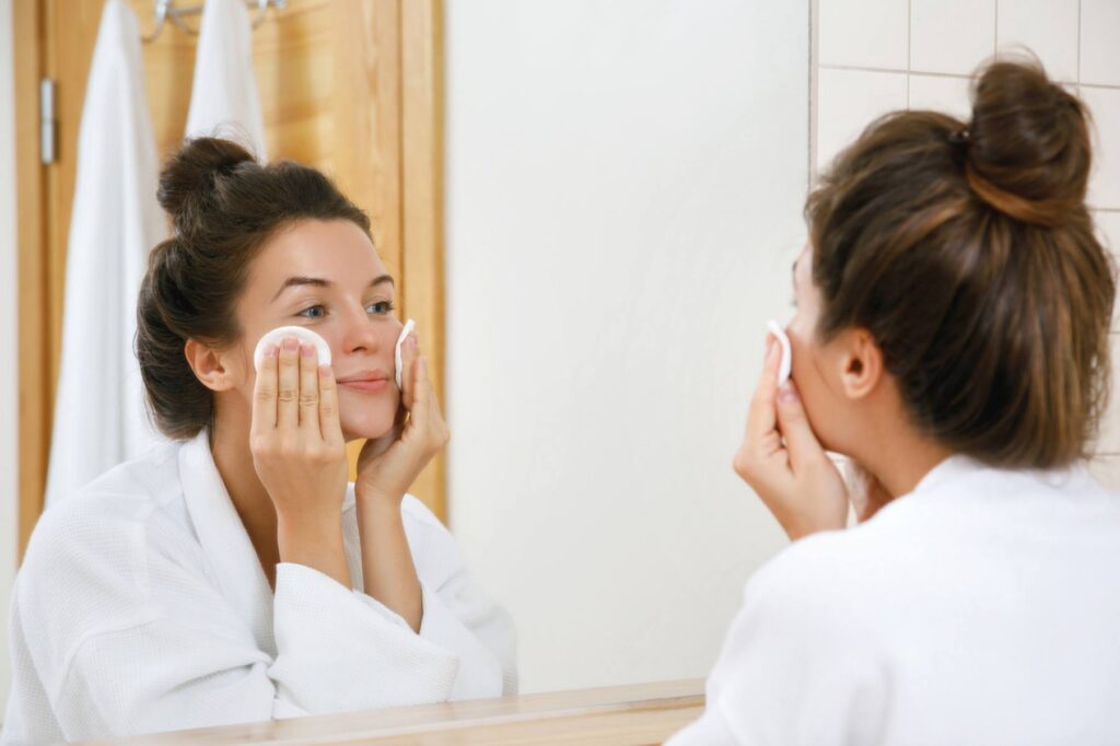 A woman applying toner to her face