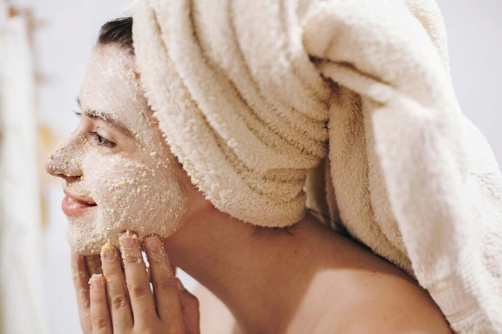 A youg girl applying scrub to her face