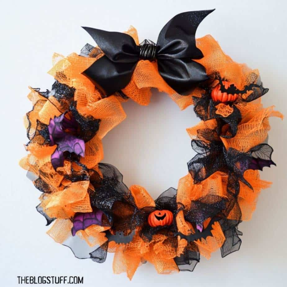 Orange and black deco mesh wreath with a satin bow and pumpkins.