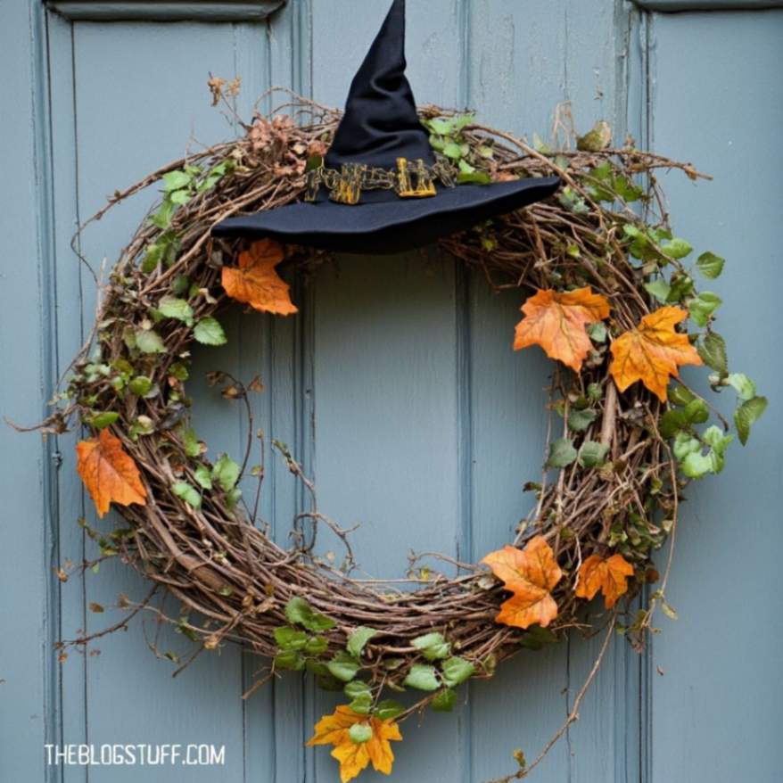 Vine wreath with a black witch hat and orange leaves.