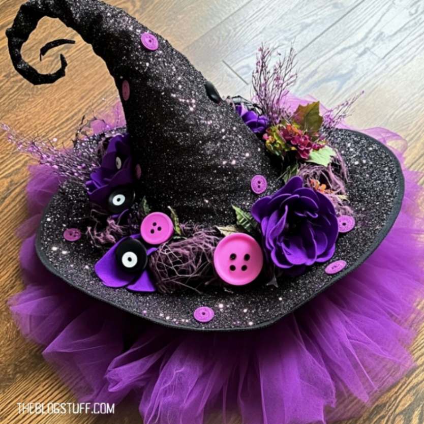 Black witch hat with purple accents, flowers, and tulle for Halloween decor.