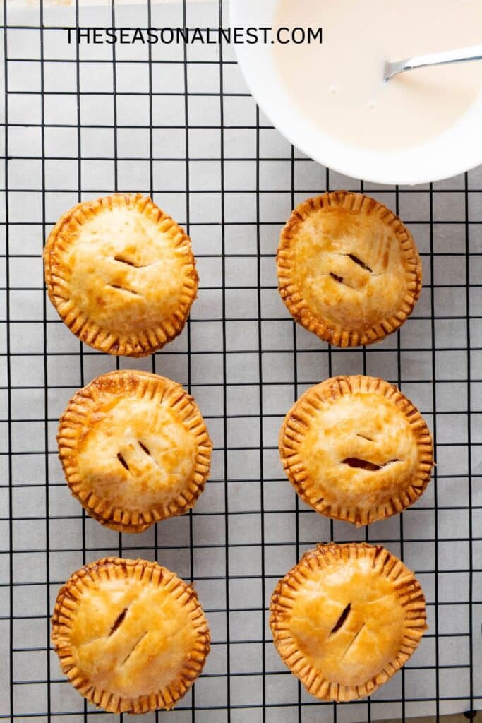 Individual apple pies cooling on a rack – small handheld apple desserts perfect for fall.